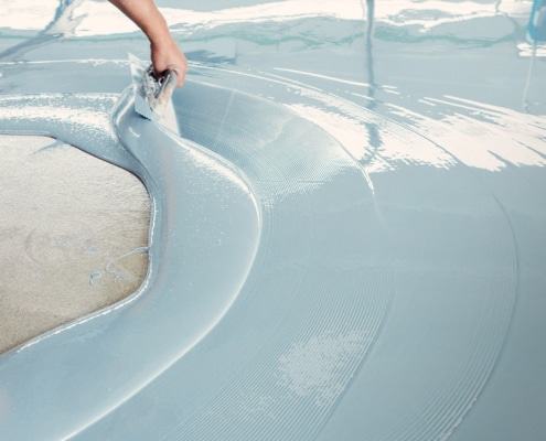 Construction worker smoothing and leveling concrete screed on the floor